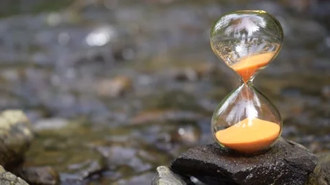 Time flows away like the water in the river. An hourglass with blur water Stock Footage 239062737
