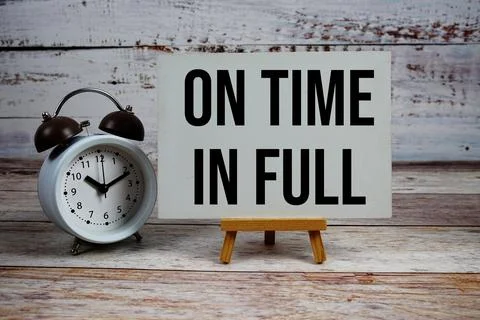 On Time In Full text with easel and alarm clock on wooden background Stock Photos
