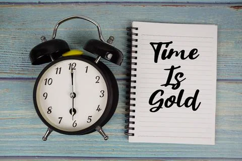 Time is Gold text written on notepad with alarm clock on wooden background Stock Photos