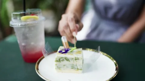 A time of happiness and ease. Asian woman eating cake in garden style cafe Stock Footage 253387159