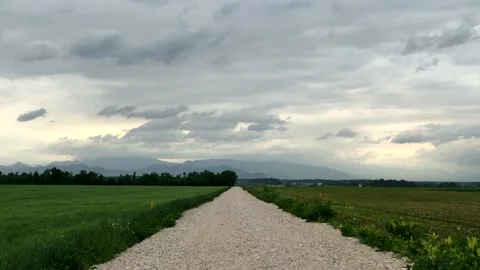 Time laps evening clouds moving over the dirt road leading to horizon Stock Footage 130592376