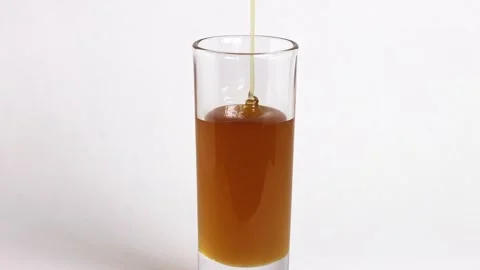 Time laps of Fresh honey flowing into a glass. Splashing honey Stock Footage 274716298