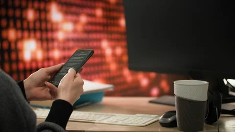 Time laps. A programmer at office desk holding mobile phone and typing on it Stock-Footage 312819058