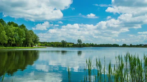 Time lapse 4k or HD - blue cloudy sky, lake, trees; zoom in Stock Footage 37918755