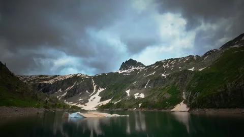 Time-lapse of alpine lake with clouds and block of last snow Stock Footage 278507037