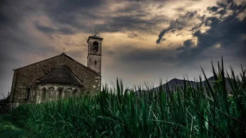 Time lapse of an ancient stone church in a field under dark storm clouds Vídeos de archivo 344699045