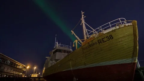 Time lapse of aurora borealis over traditional wooden trawler in dock at port Stock Footage 73079822