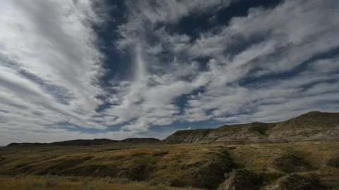Time lapse of autumn clouds moving above a dry grassy prairie badlands setting Stock Footage 297004208