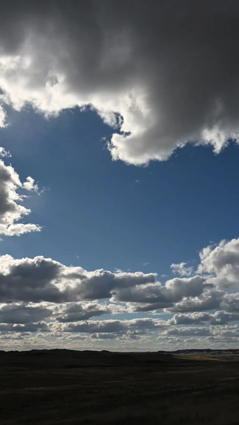 Time lapse of backlit summer clouds drifting above a dry prairie ranch landscape Stock Footage 306541767