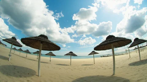 Time lapse, Beautiful beach with straw umbrellas on the sandy seashore. Stock Footage 228999326