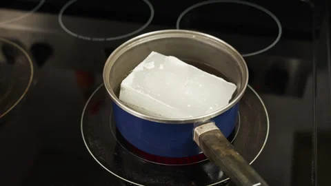 Time lapse of a block of wax melting on a pan on the stove Stock Footage 255767005