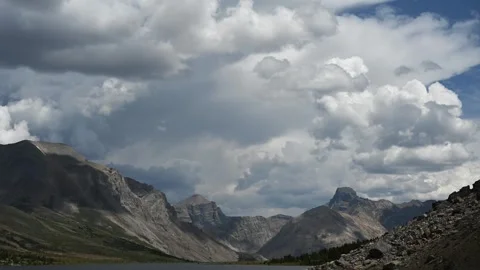Time lapse of blowing storm clouds moving above a large mountain range in Banff Stock Footage 328428125
