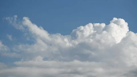 Time lapse of bright white cumulus clouds rising and drifting across a deep blue Stock Footage 329239263