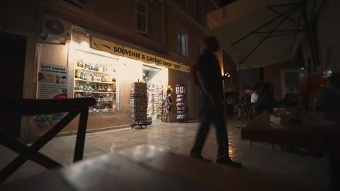 Time lapse of busy old town alley in Zadar at night with souvenir shop closing Vídeo Stock 343895269