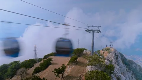 Time lapse: cable car cabins moving over mountain terrain, fast moving clouds Stock Footage 319046999