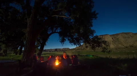 Time lapse - campers around campfire next to river with stars overhead Video stock 65010910