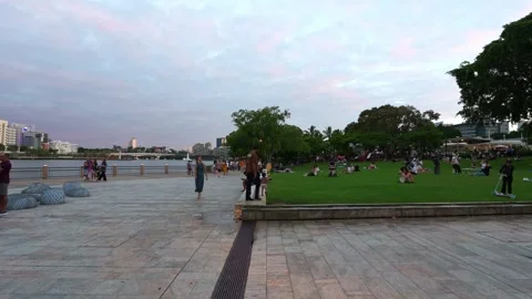 Time-lapse capturing people walking along a wide, paved riverside promenade in Stock Footage 341311161