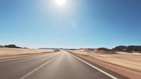 Time lapse car driving on empty desert highway with rocky hills under clear blue Vidéo 326023646