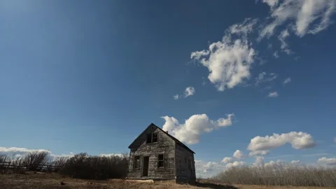 Time lapse of churning summer clouds in blue sky above an abandoned farmhouse Stock Footage 307626856