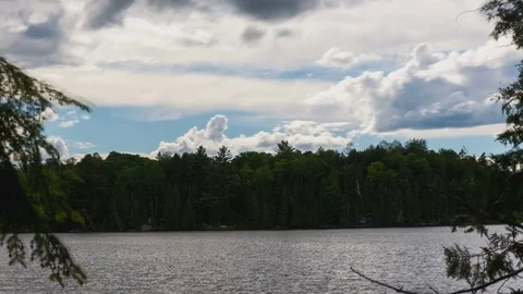 Time lapse of clouds above a lake framed by trees Stock Footage 79696759