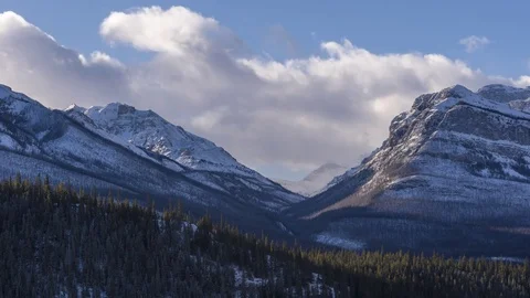 Time lapse of clouds above snowy mountain peaks and green forest Video stock 85252205