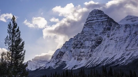 Time lapse of clouds above snowy mountain peaks and green forest Video stock 85252321