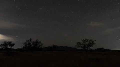 Time lapse of clouds and stars and a moonlight reveal of the desert Stock Footage 321366341