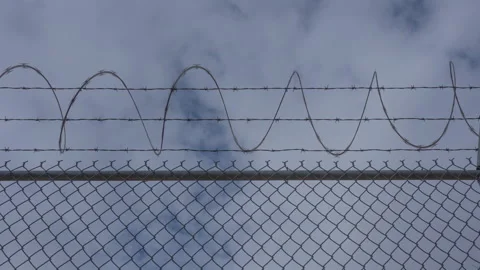 Time lapse of clouds beyond a prison yard fence Stock Footage 228698763