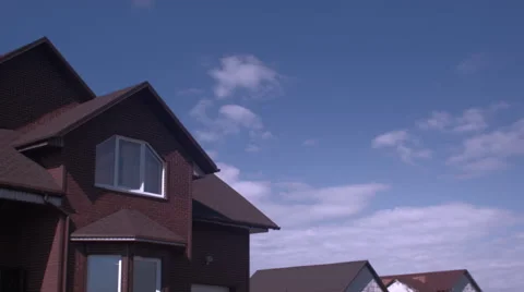 Time-lapse clouds in blue sky over roof of the brown house Video stock 62973132