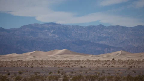Time lapse of clouds in blue sky above the Mesquite sand dunes in Death Valley Stock Footage 147510717