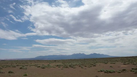 Time lapse of clouds in blue sky above dry plains and distant La Sal Mountains Stock Footage 151657413