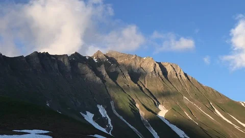Time lapse clouds float across the blue sky over the snowy tops of the mountains Stock Footage 111867264