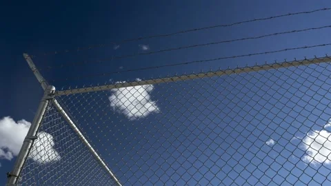 Time lapse of clouds floating above a security fence Stock Footage 168686460