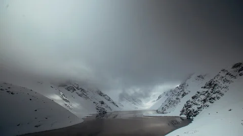 Time-lapse of clouds floating over snowy mountains and a frozen lake Stock Footage 113246756