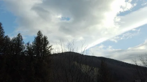 Time lapse of clouds flowing across the blue sky over the tops of mountains.  Stockbeeldmateriaal 125817377