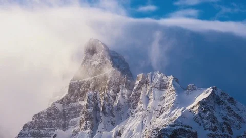 Time lapse clouds flowing over snowy mountain peak at sunrise Video stock 72732473