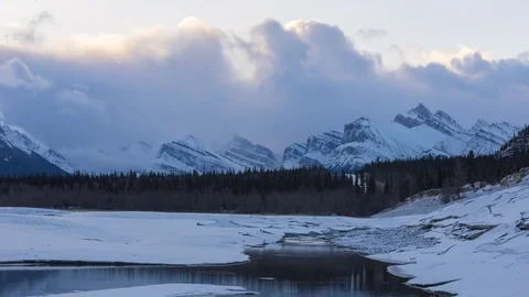 Time lapse of clouds flowing over snowy mountain peaks at sunrise Stock Footage 84926729