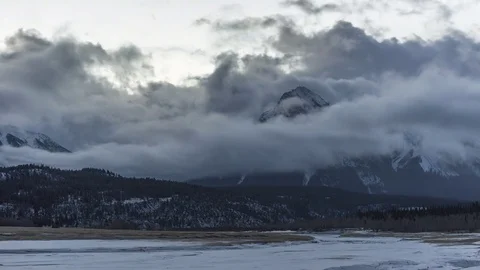 Time lapse of clouds flowing over snowy mountain peaks at sunrise Stock Footage 84933817