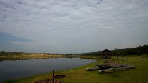 Time lapse of clouds going across a dam with a raft on the shore Stock Footage 155385780
