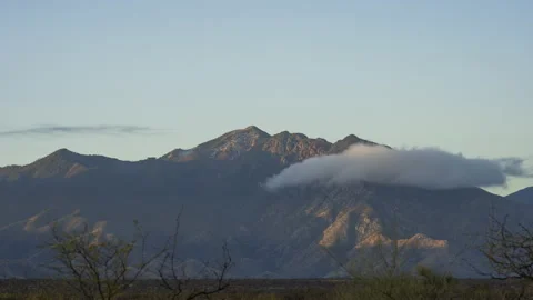 Time lapse of clouds hugging a majestic mountain in the morning light Stock Footage 237002641
