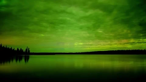 Time lapse of clouds lite green by Aurora as they move above a large calm lake. Stock Footage 289205445