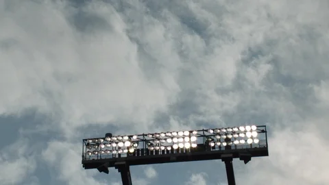 Time-lapse of clouds moving above illuminated stadium lights Stock Footage 104772839
