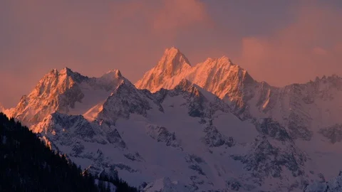 Time-lapse of clouds moving above snow capped mountains during sunrise Stock Footage 116742787