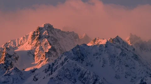 Time-lapse of clouds moving above snow capped mountains during sunrise Stock Footage 116742837