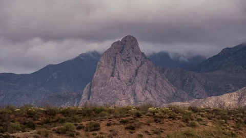 Time lapse of clouds moving behind a towering rock monolith in the desert Stock Footage 325512909
