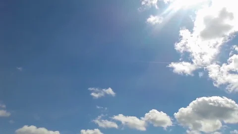 Time lapse of clouds moving in blue sky, airplane passing by and sunbeam Stock Footage 76598949