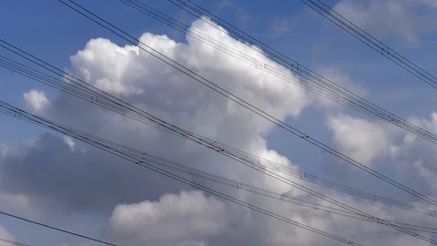 Time Lapse: clouds moving in blue sky, changing shape, seen through power lines Stock Footage 94624771