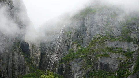 Time-lapse of clouds moving in front of huge rock face with high waterfall Video stock 112666169
