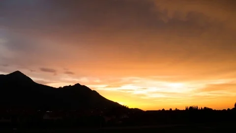 Time lapse of clouds moving in the orange sky over the mountains Stock Footage 77815506