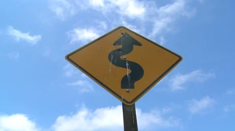 Time lapse of clouds moving over a road sign warning of curves ahead. Stock Footage 942021